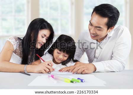 Young asian girl studying at home by help her parents