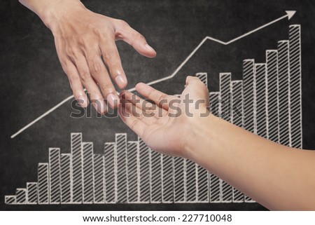 Helping hand with business growth graph on blackboard