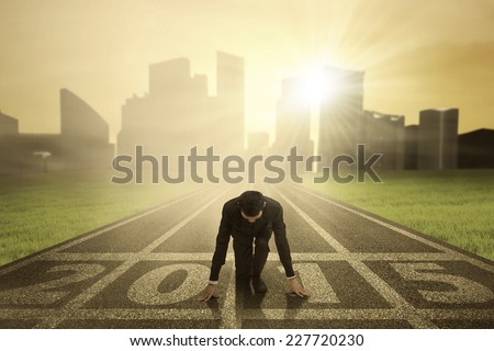 Man kneeling on track and ready to chase his dream in the future 2015