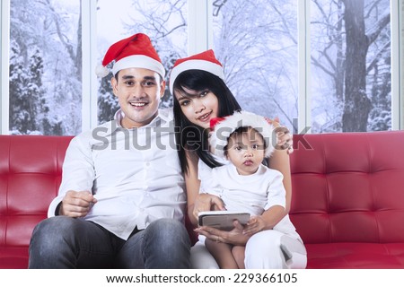 Cheerful family looking and smiling on the camera while using a digital tablet in christmas day at home