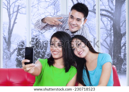 Young asian teenager using a smartphone to take self portrait at home in winter day