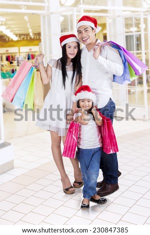 Happy family standing in the mall while carrying shopping bags