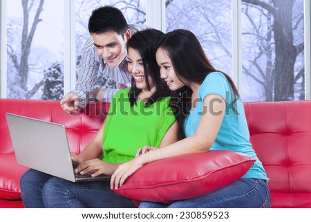 Portrait of asian students sitting on sofa and using a notebook together with winter background on the window