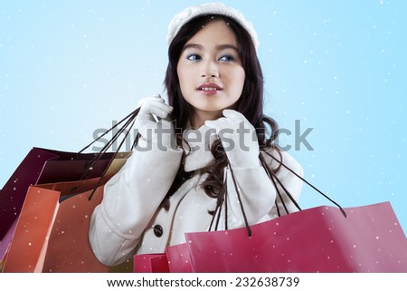 Young asian woman wearing winter jacket while carrying lot of shopping bags
