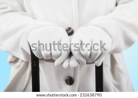 Closeup of woman hands in winter gloves and warm clothes, holding a luggage hand grip