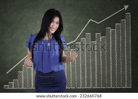 Asian businesswoman expressing her success in front of growth business chart