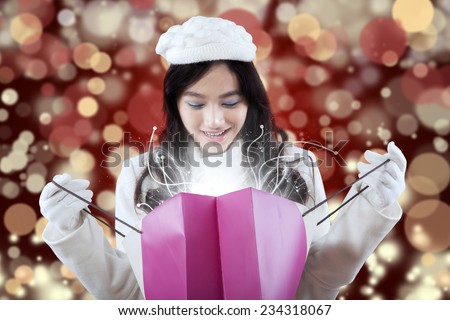 Cheerful girl looking at the shopping bags with miracle light, shot with light glitter background