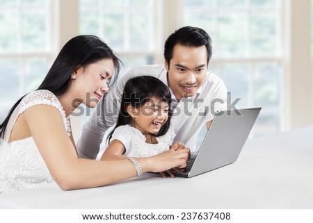 Portrait of happy family using laptop computer together at thome while smiling happy