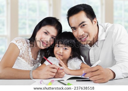 Portrait of happy family doing homework together at home and smiling at the camera