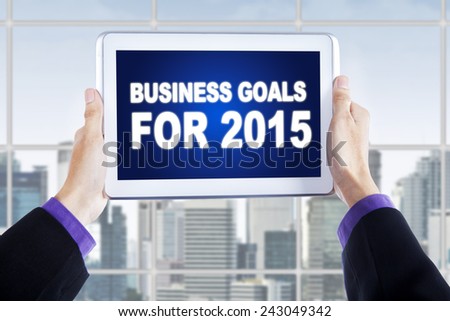 Entrepreneur hands holding a digital tablet with a text of business goals for 2015