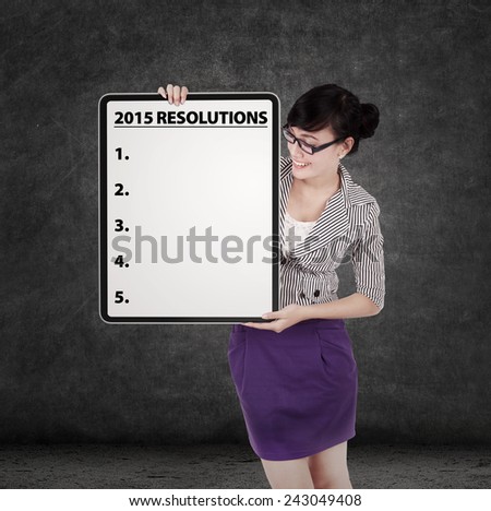 Young businesswoman holding a board to write a list of business resolution in 2015