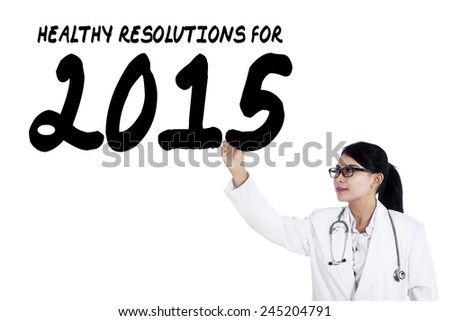 Young female physician with stethoscope writes health resolution for 2015 on whiteboard