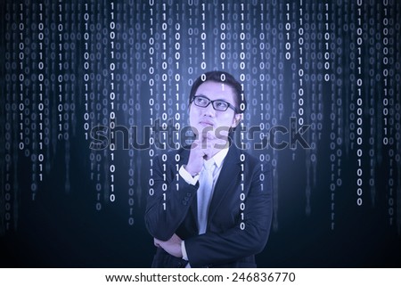 Young male entrepreneur in business suit, looking at binary code in futuristic computer screen
