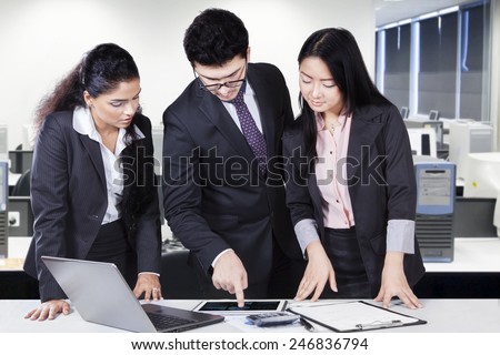 Male business leader explaining financial chart on digital tablet to his partners