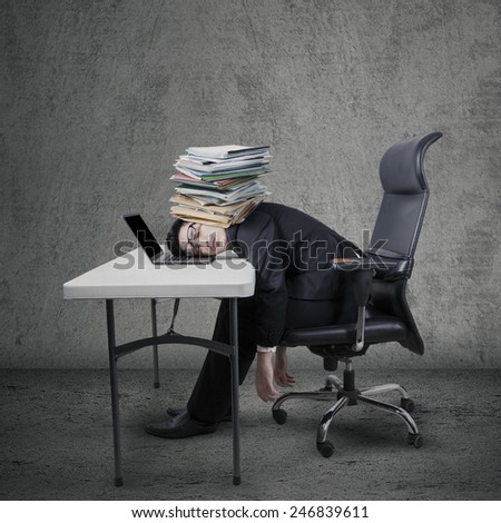 Exhausted young entrepreneur sleeping on laptop computer at table