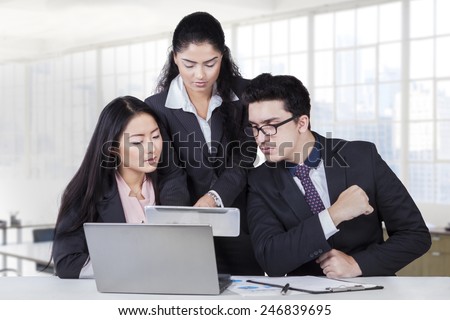 Portrait of young business leader showing business plan on tablet at her team in the business meeting