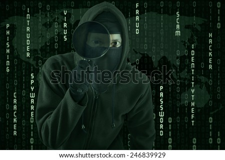 Male hacker looking for information with magnifying glass while wearing a mask