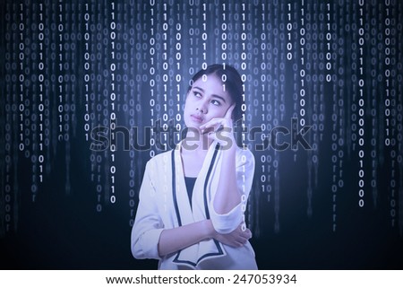 Young asian businesswoman thinking in front of computer screen with binary code