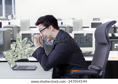 Happy caucasian entrepreneur looking money dollars on laptop computer at office