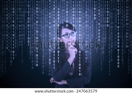 Young asian female entrepreneur looking at computer screen with binary code