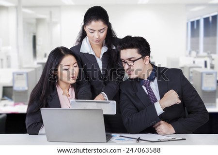 Female employee sharing business information on the tablet with her partners in the office