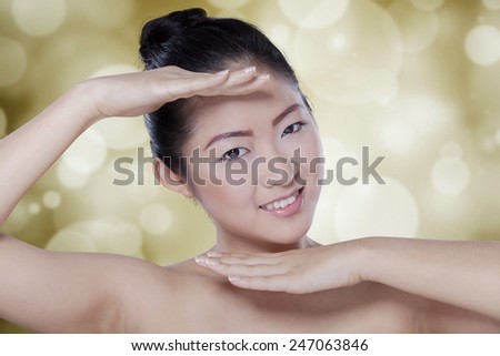 Attractive chinese girl with clean skin plays her hands while smiling at the camera
