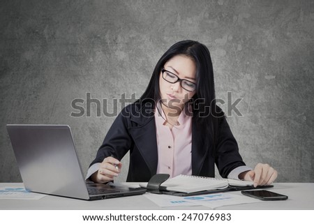 Young female entrepreneur working on desk with planner book and laptop computer