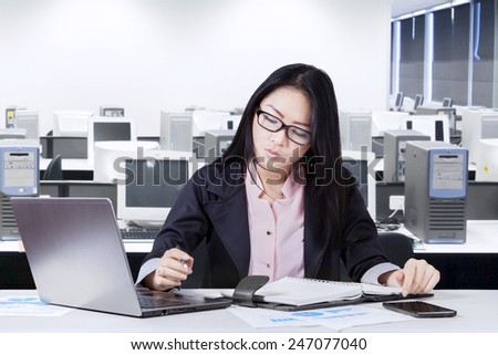 Young chinese businesswoman working in the office while making a plan on notebook