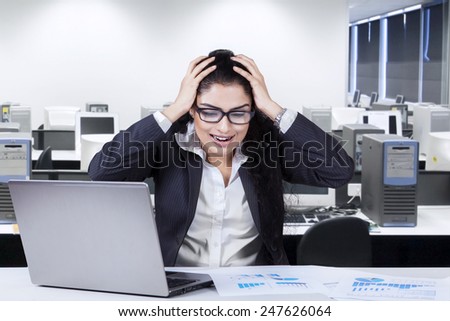 Stressful businesswoman shouting at her job on the table, shot in the office