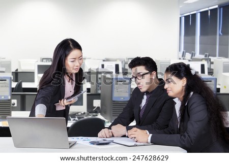 Portrait of chinese businesswoman explaining a business plan to her team in the office
