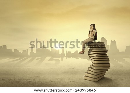 Young female student sitting and dreaming her future above books