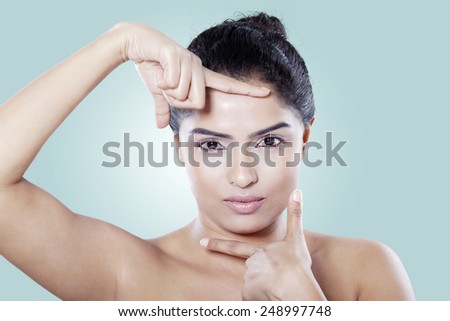 Attractive of young woman with hands gesture in front of her fresh skin, shot in the studio