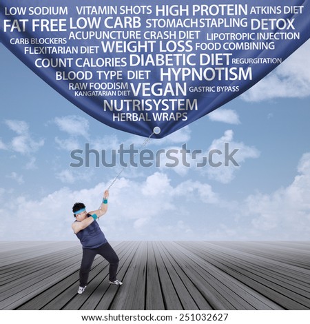 Fat man pulling a weight loss banner, shot outdoors