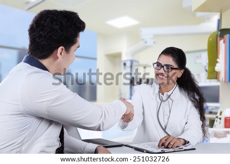 Attractive friendly doctor shaking hands with her patient, shot in the hospital