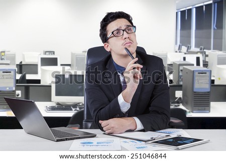Attractive young businessman working in the office while concentrate to find an idea