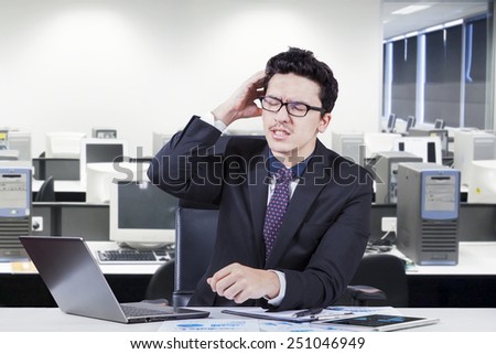 Caucasian businessman with confused expression doing his job with laptop on desk