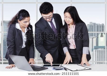 Male entrepreneur using a digital tablet to explain financial chart on his employees