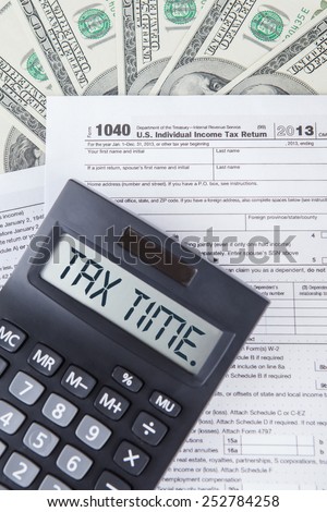 Closeup of tax time word with tax form, dollars cash, symbolizing the time to pay tax