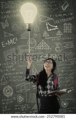 Attractive college student turn on the light in the class with the blackboard full of the scribble