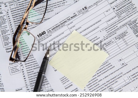 Closeup of an empty paper note with tax form and glasses