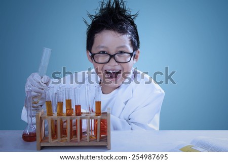 Cute asian boy wearing lab coat doing experiment like a mad scientist