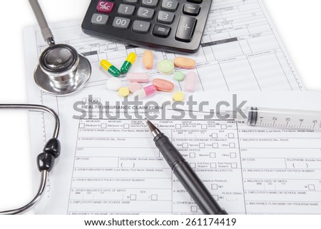 Paperwork of health insurance claim form on the table with stethoscope, pen, drugs, syringe, and calculator