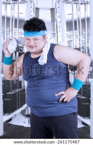 Portrait of fat person with sportswear using a towel to clean his sweat after workout in fitness center