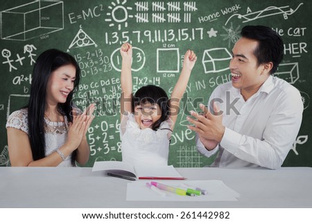 Cheerful little girl get appreciation and applause from her parents after studying