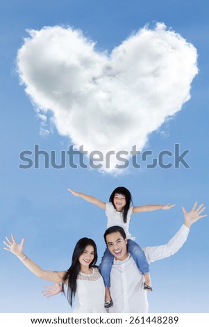 Portrait of cheerful family raise hands together and enjoy freedom under cloud shaped heart