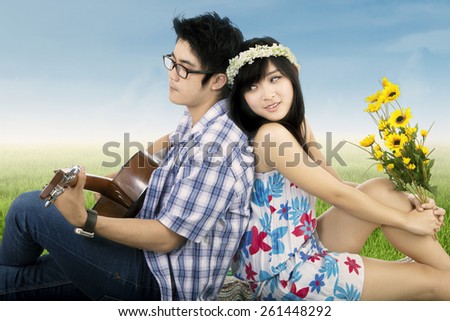 Portrait of happy couple enjoy holiday together by playing guitar on the meadow
