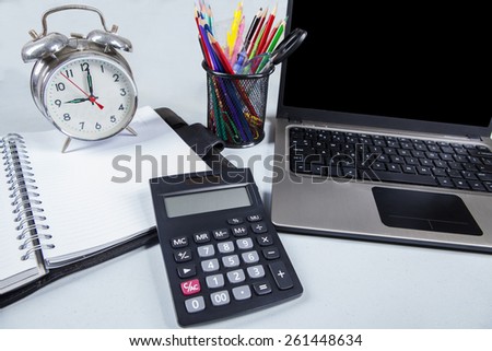 Work equipments on the modern office desk with laptop, calculator, alarm clock, and stationery