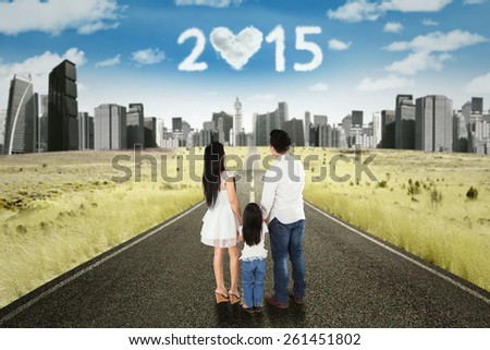 Back view of family standing on the road while looking at cloud shaped numbers 2015