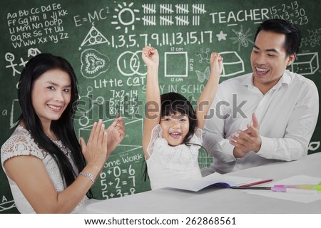 Portrait of happy little girl raise hands after finish her homework and get applause