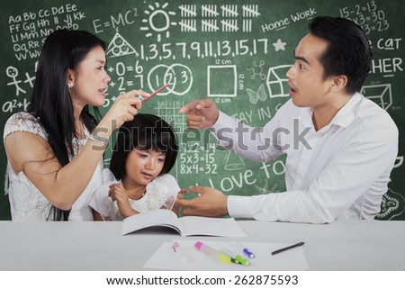 Portrait of little girl crying while her parents quarreling when help their child to study